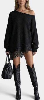 Mahaute black oversized knit sweater dress with off-the-shoulder neckline and floral lace hem, worn with tall boots.