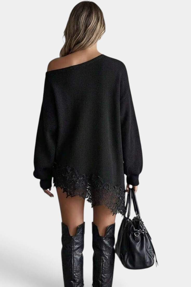 Mahaute black oversized knit sweater dress with off-shoulder neckline and floral lace hem, worn with tall boots.