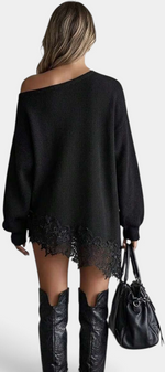 Mahaute black oversized knit sweater dress with off-shoulder neckline and floral lace hem, worn with tall boots.