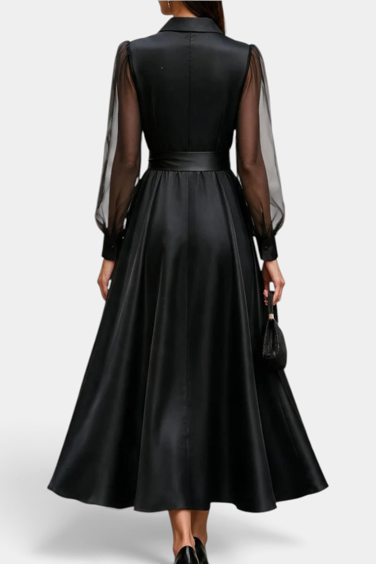 Back view of Mahaute Eirene midi dress in black satin with sheer long sleeves, shirt collar, and a tied waist.