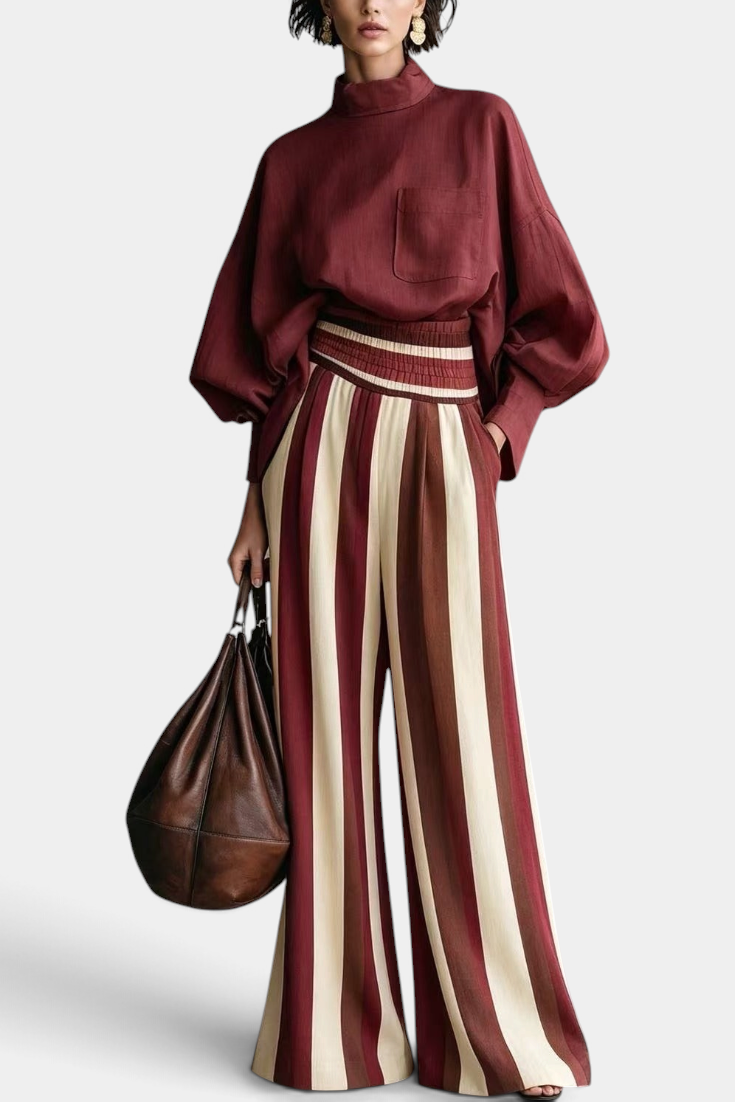 Mahaute Orlianne burgundy blouse with puff sleeves and high-waisted wide-leg striped trousers.