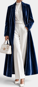 Mahaute long blue velvet coat with elegant lapels, worn over a white outfit with a matching handbag.