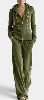 Ensemble Mahaute Cassiane avec veste à capuche zippée, boutons dorés et pantalon large, porté en scène mode élégante.