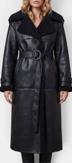 Manteau long noir Mahaute Alixane en faux cuir avec col fourré et ceinture, style élégant et tendance.