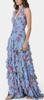 Robe longue fleurie Mahaute Amaya avec dos nu, volants cascade et motif floral bleu, portée élégante et féminine.