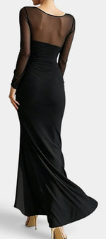 Robe longue noire Mahaute Apolonia avec décolleté cœur, manches transparentes et fente élégante.