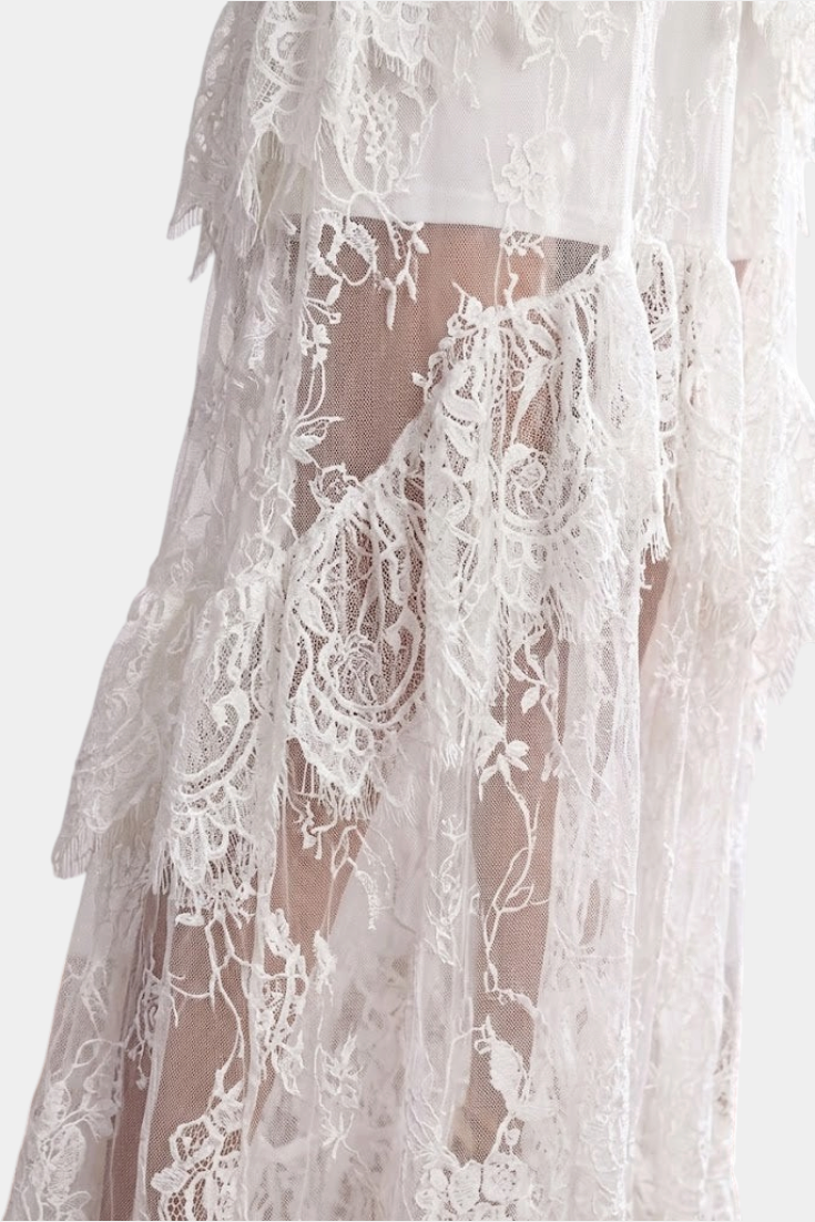 Mahaute Atalisse long white lace dress featuring intricate floral patterns, layered ruffles, and sheer transparency.