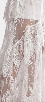 Mahaute Atalisse long white lace dress featuring intricate floral patterns, layered ruffles, and sheer transparency.