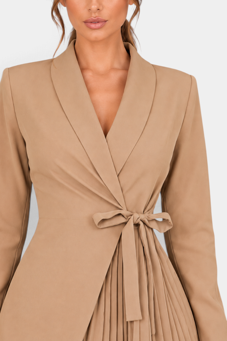 Mahaute Alexandra beige blazer dress with a wrap-front, tie waist, and pleated skirt detail on a model