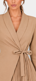 Mahaute Alexandra beige blazer dress with a wrap-front, tie waist, and pleated skirt detail on a model