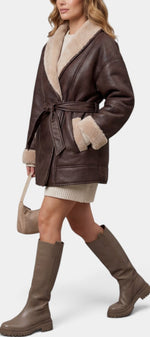 Manteau court Mahaute Belgrade en cuir synthétique marron avec ceinture, doublure polaire contrastante, style aviateur.
