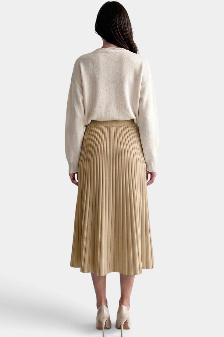 Jupe plissée longue beige à taille haute et coupe évasée de la marque Mahaute, portée avec un haut blanc.