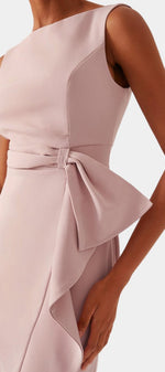 Mahaute Billini midi dress in blush pink featuring a boat neckline, side tie waist, and elegant asymmetrical drape.