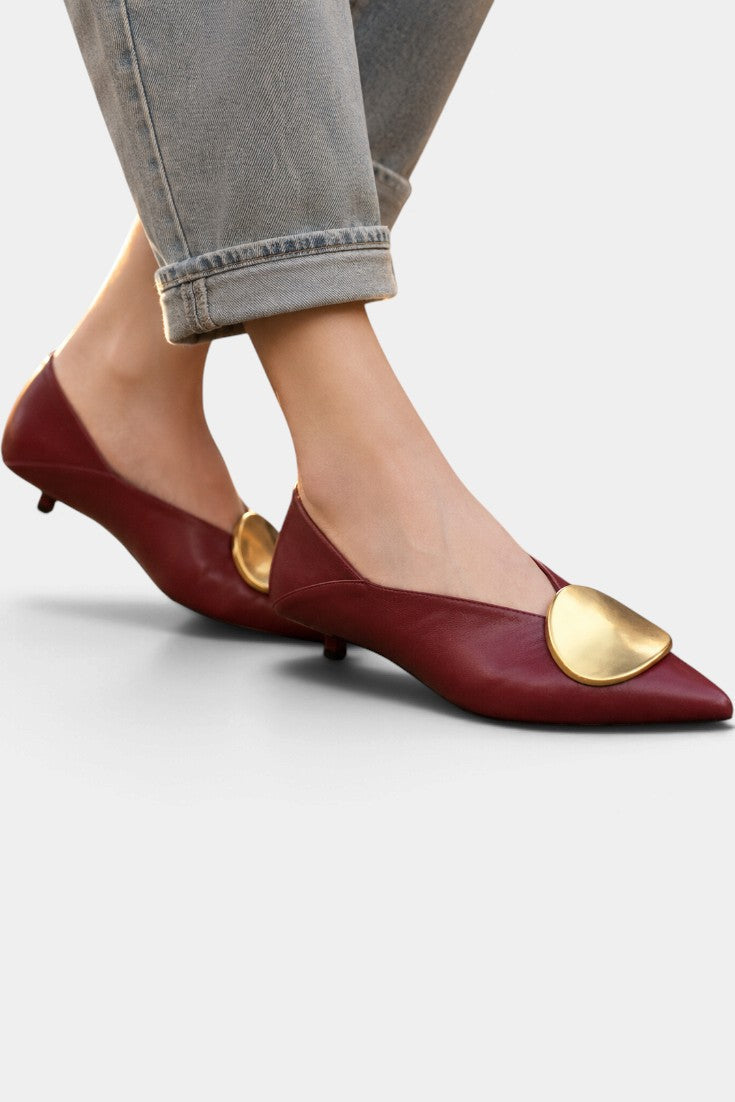 Mahaute Billini burgundy pointed-toe kitten heels with a large gold metallic ornament worn with cropped jeans