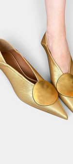 Mahaute Billini gold pointed-toe pumps with a low heel and large circular metallic ornament on the front