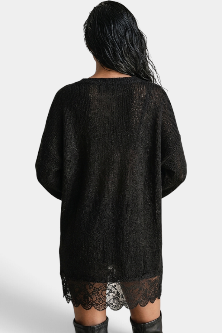 Back view of a model wearing a Mahaute black oversized knit sweater dress with a delicate floral lace hem.