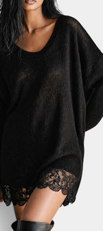 Mahaute black oversized knit sweater dress with a scoop neckline and delicate floral lace hem worn by a model