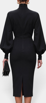 Back view of a Mahaute black midi pencil dress with a high neck and voluminous balloon sleeves, worn outdoors.