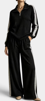 Mahaute black ribbed knit lounge set with zip-up sweater and wide-leg trousers featuring contrasting side stripes.