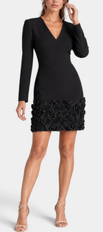 Mahaute Bilyana black short dress with long sleeves, V-neck, cinched waist, and 3D floral applique hem on a model.