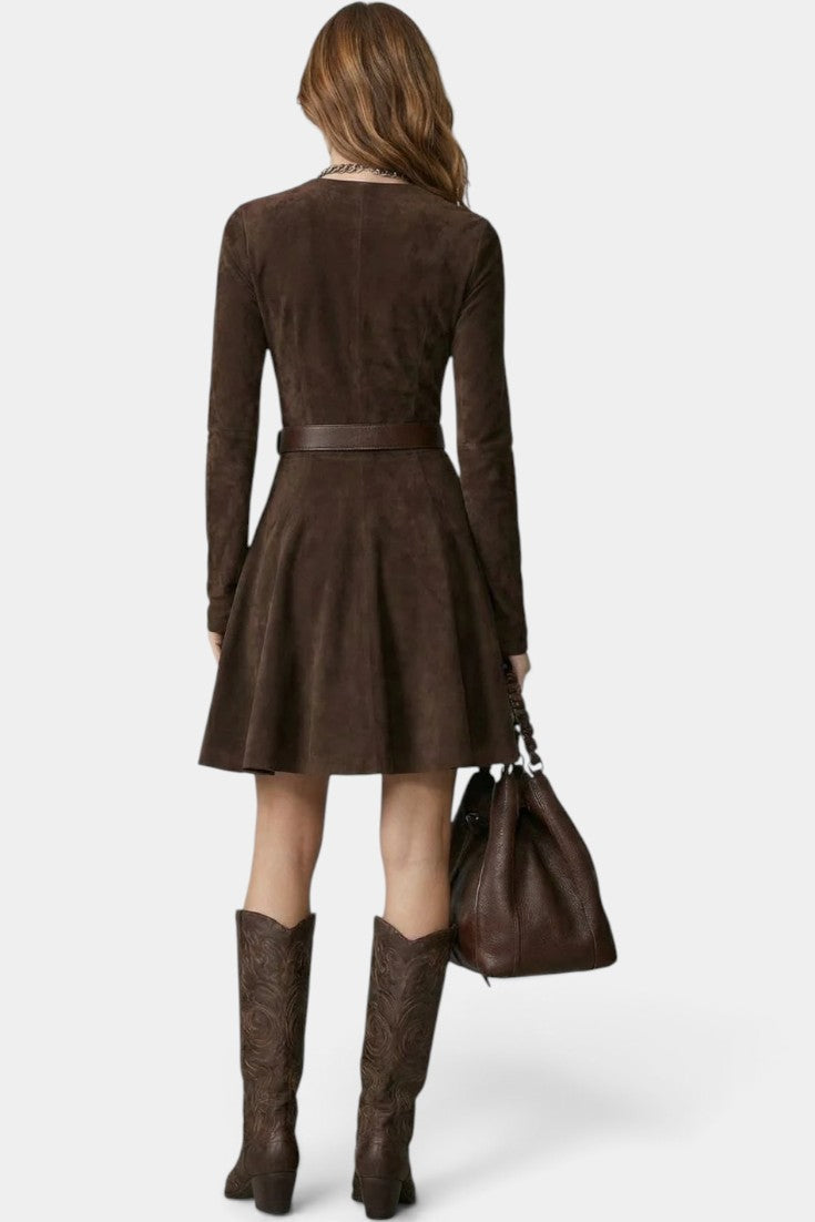 Back view of a woman wearing a Mahaute brown suede skater dress with a belted waist, long sleeves, and cowboy boots.