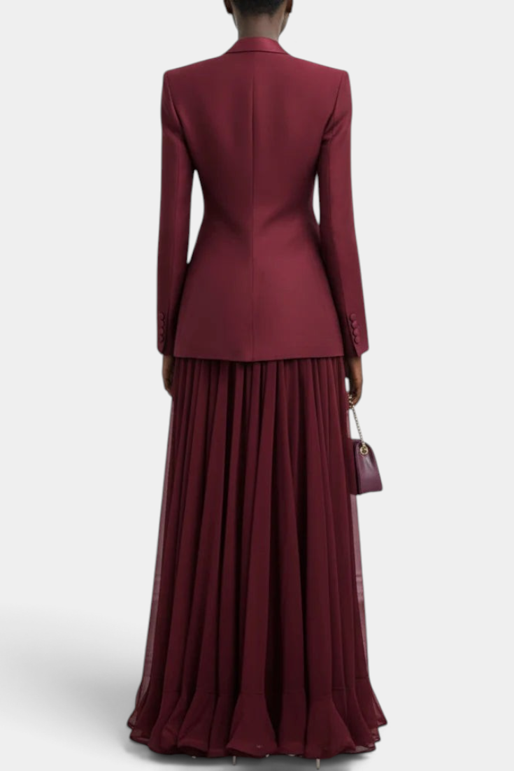 Back view of a Mahaute burgundy two-piece set featuring a structured blazer and a long pleated flowing maxi dress.