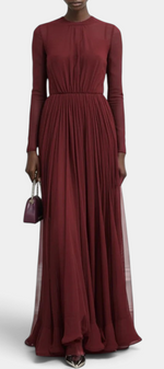 Mahaute burgundy long-sleeved pleated maxi dress with a high neckline worn by a model holding a small clutch bag