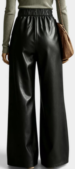 Back view of Mahaute Camellia wide-leg trousers in black faux leather with an elasticated waist