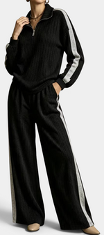 Mahaute Cocoon black ribbed knit lounge set with zip-up sweater and wide-leg trousers featuring contrast side stripes.
