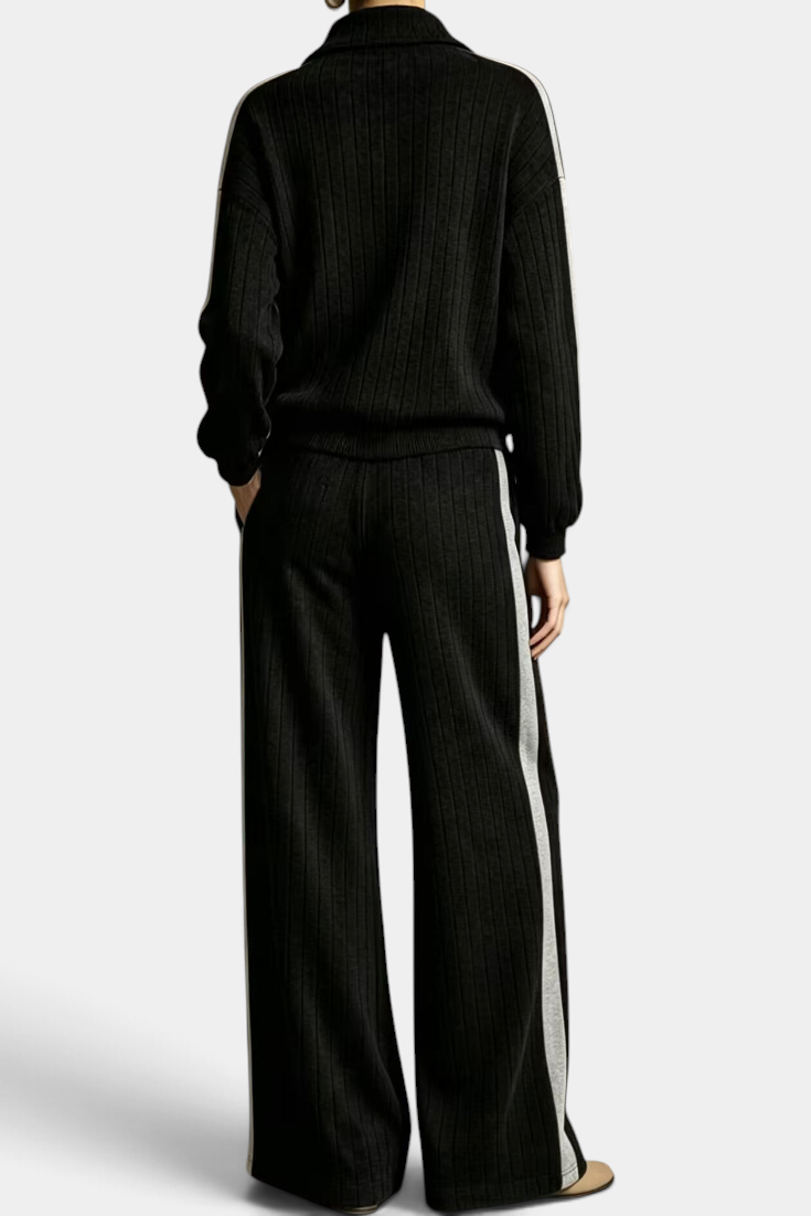 Mahaute Cocoon black ribbed knit lounge set with zip-up sweater and wide-leg trousers featuring contrast side stripes.
