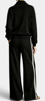 Mahaute Cocoon black ribbed knit lounge set with zip-up sweater and wide-leg trousers featuring contrast side stripes.