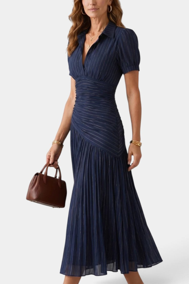 Robe mi-longue Dimitri de Mahaute à rayures bleues, plissée, avec col chemise et taille drapée, portée de profil.