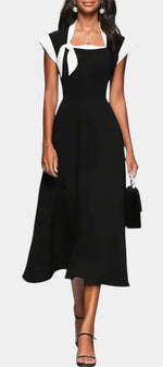 Robe mi-longue noire Mahaute Dolores avec col carré, nœud contrasté et manches courtes, élégante et féminine.