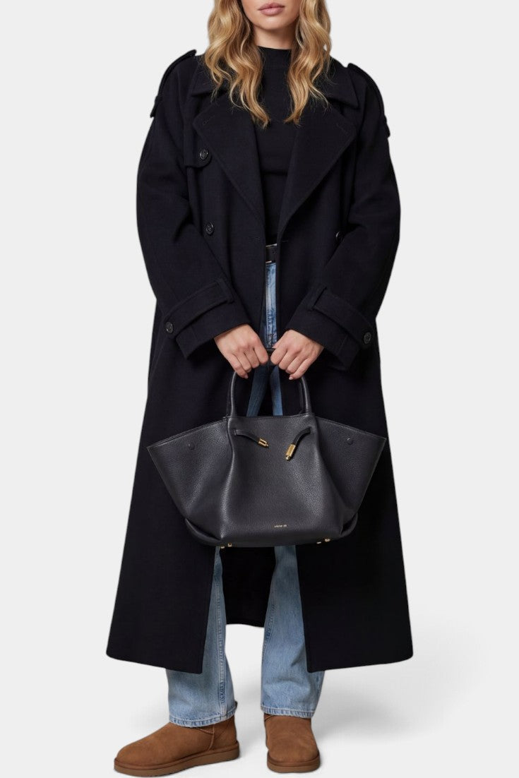 Manteau trench long noir Mahaute Dymphna avec ceinture, double boutonnage et épaulettes, porté sur un mannequin.