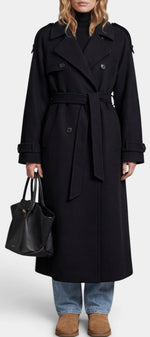 Mahaute Dymphna trench long noir avec ceinture, double boutonnage et épaulettes, porté sur un mannequin.