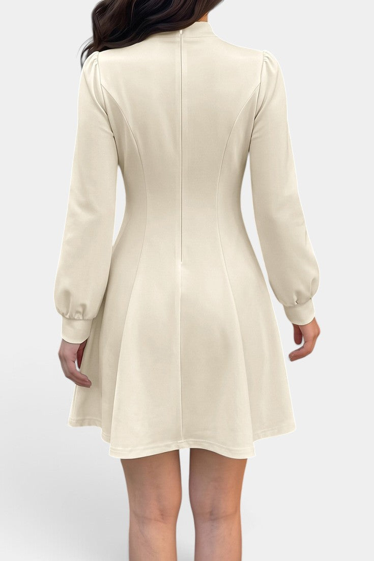 Robe courte Mahaute Edelmira évasée crème avec col montant, découpe goutte et manches longues, style élégant et féminin.