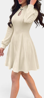 Robe courte évasée Mahaute Edelmira couleur crème avec col montant, découpe goutte et manches longues, portée sur mannequin.