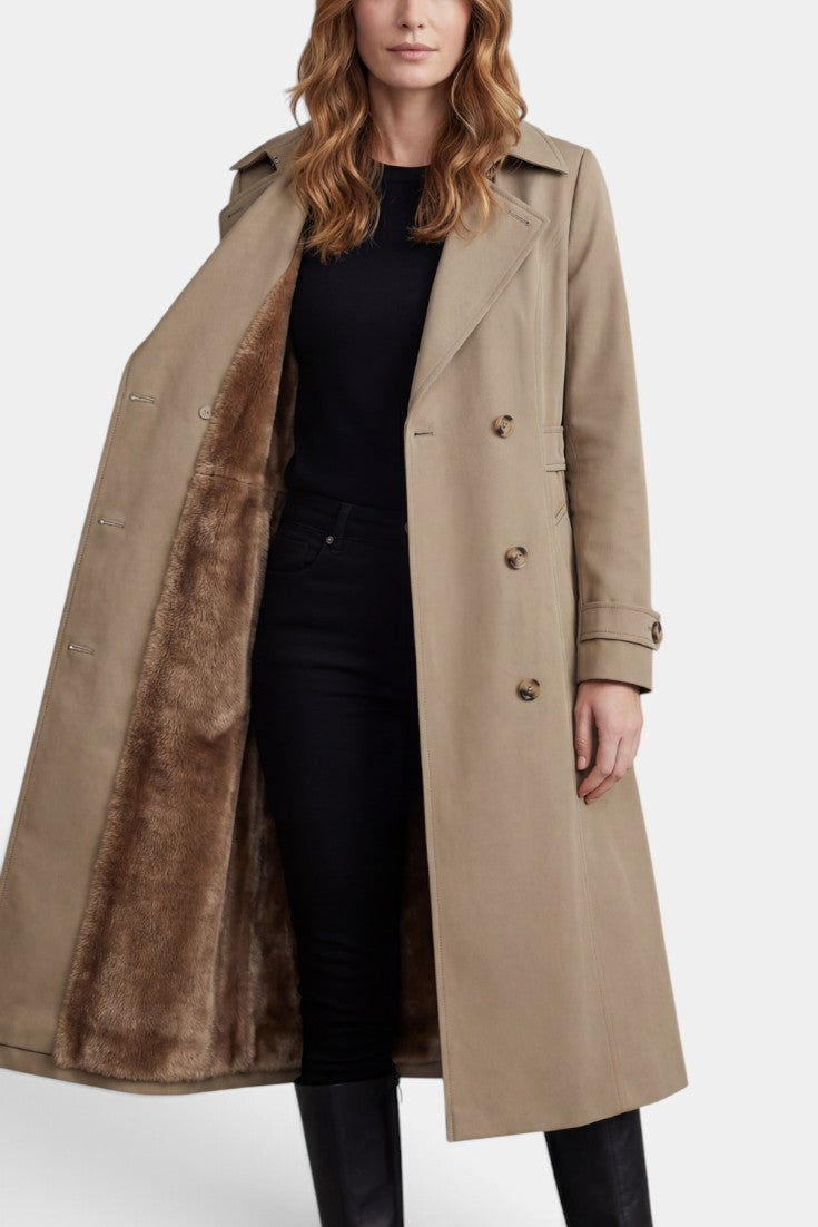 Mahaute Ermelinde trench long beige à doublure fourrure, ceinturé, avec double boutonnage, porté avec col relevé et poches latérales
