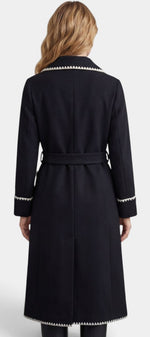 Manteau long noir Mahaute Euphrasie avec ceinture, col tailleur et finitions contrastées, porté sur un mannequin.