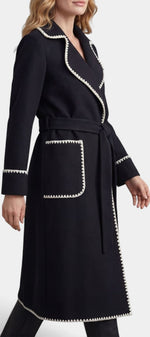 Manteau long noir Mahaute Euphrasie avec ceinture, col tailleur et finitions contrastées, élégance et style intemporel.