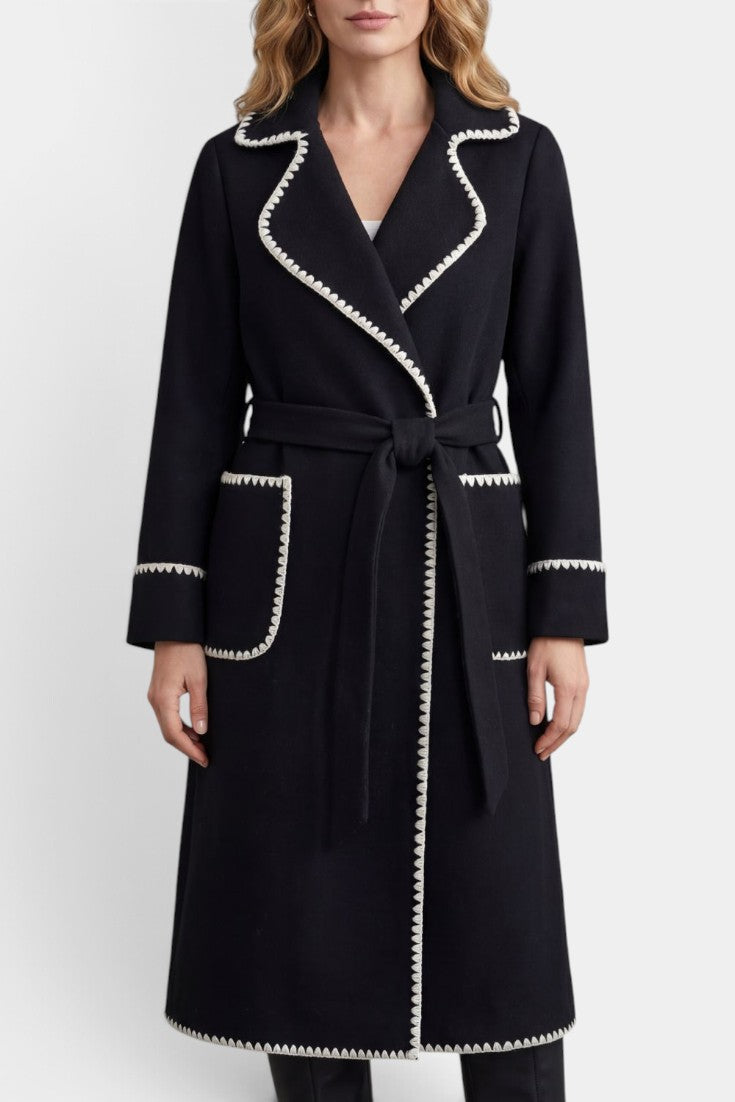 Manteau long noir Mahaute Euphrasie avec ceinture, col tailleur et finitions contrastées, style élégant et sophistiqué.