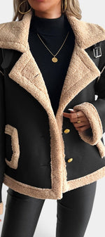 Mahaute Flynn short black faux suede coat with beige faux fur collar, cuffs, and gold buttons worn by a woman.