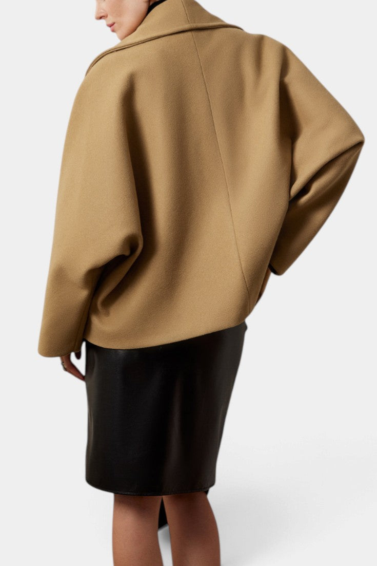 Back view of Mahaute Helena camel short coat with shawl collar worn over a black skirt