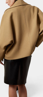 Back view of Mahaute Helena camel short coat with shawl collar worn over a black skirt