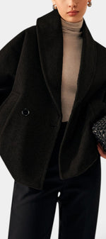 Mahaute Helena black short wool coat with wide shawl collar and double-breasted design worn over a beige turtleneck