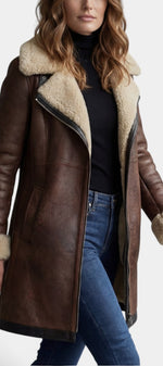 Manteau mi-long en faux cuir marron Hildegarde de Mahaute avec col fourré et fermeture éclair, style élégant et moderne.