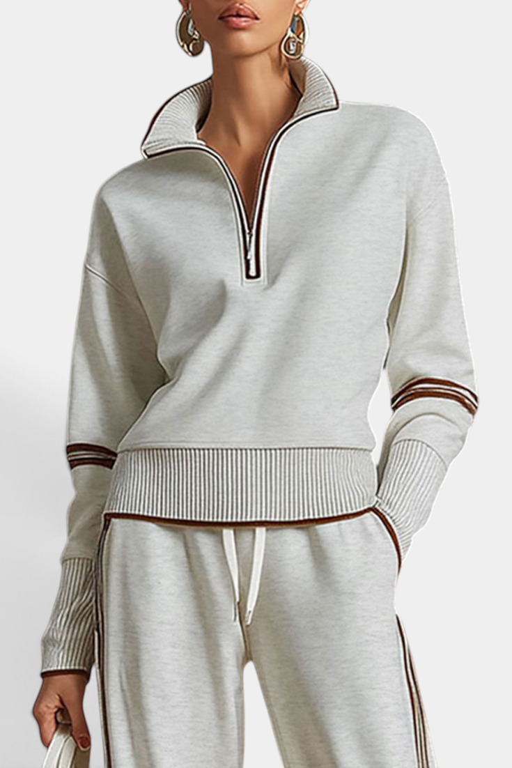 Mahaute Ismay beige knit lounge set with a zip-up mock neck, ribbed cuffs, and brown contrast side stripes.