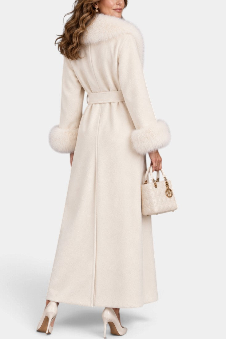Mahaute Lalie long cream belted coat with faux fur collar and cuffs worn by a woman with a matching handbag