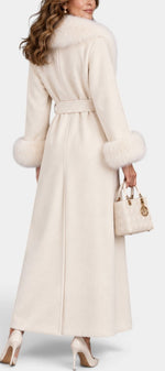 Mahaute Lalie long cream belted coat with faux fur collar and cuffs worn by a woman with a matching handbag