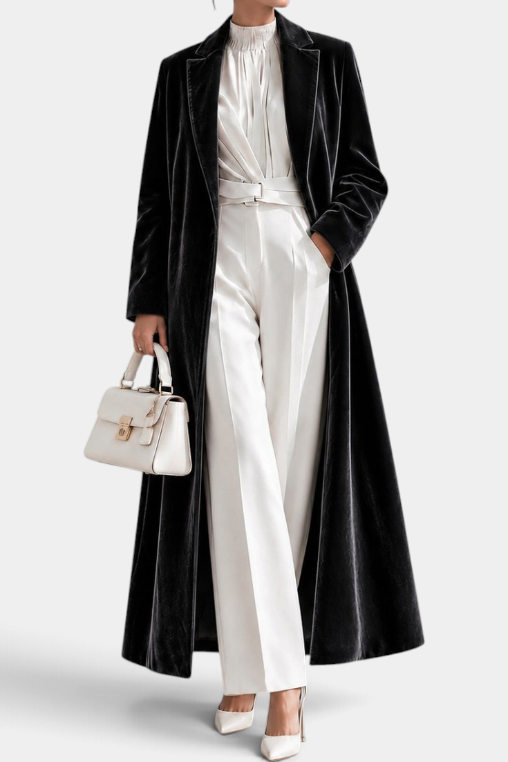Mahaute long black velvet coat with elegant lapels, worn over a white blouse and trousers for a sophisticated look.